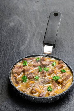 Siyah taş arka planda tavada sebzeli sığır eti yahnisi. 