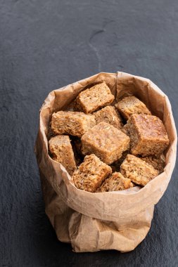 Mini yulaf ve şurup siyah taş arka planda kağıt torbaya dilimler. 