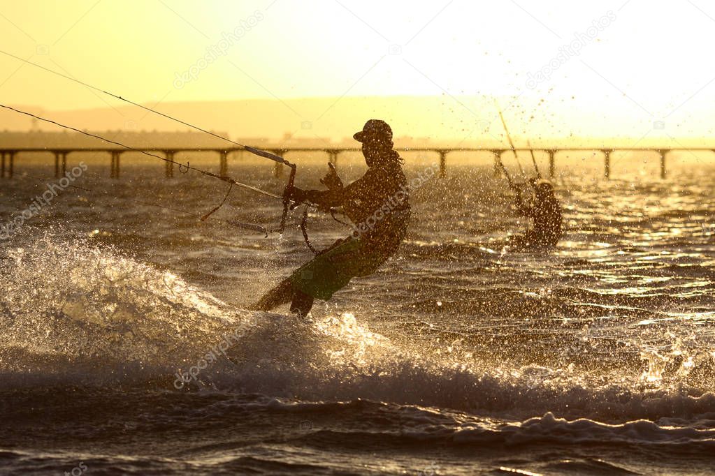 Kiteboarder sportsman under sunset sun, freestyle kiteboarding rider on the evening kitesession