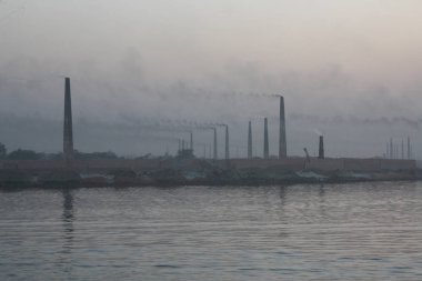 Buriganga Nehri kıyısındaki tuğla fabrikaları. Bu fabrikaların bacalarından çıkan kara duman çevreye ve ekosisteme ciddi bir tehdit oluşturuyor. Dhaka, Bangladeş