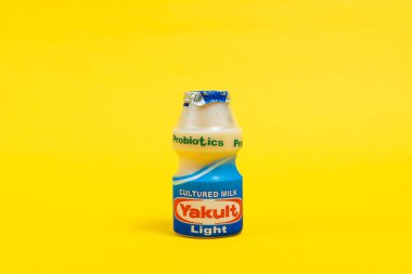 Makati city of Manila, Philippines. Mar 09 2020: Yakult and Yakult Light fermented milk drink on yellow isolated background. Healthy probiotic drink with the bacteria strain Lactobacillus paracasei Shirota.