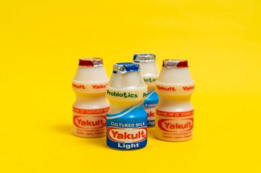 Makati city of Manila, Philippines. Mar 09 2020: Yakult and Yakult Light fermented milk drink on yellow isolated background. Healthy probiotic drink with the bacteria strain Lactobacillus paracasei Shirota.