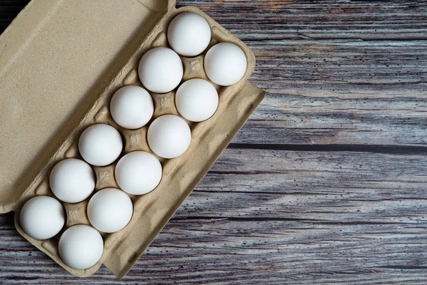 Chicken eggs in egg box on wooden rusty background