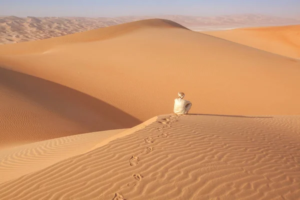 Arab człowiek w stroju tradycji siedzi nad Dune w arabskiej pustyni — Zdjęcie stockowe