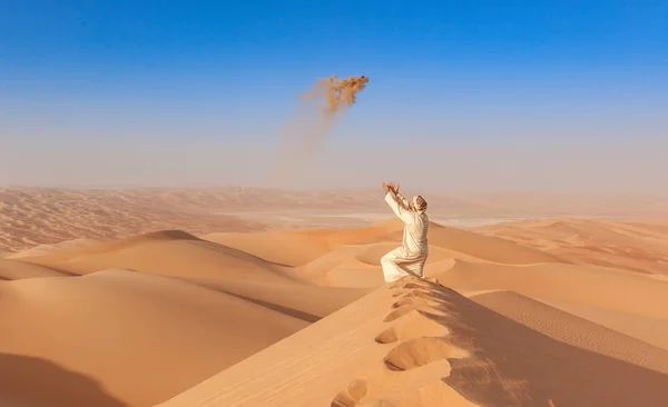 Arab man dalam pakaian tradisional melemparkan pasir di udara arabian — Stok Foto