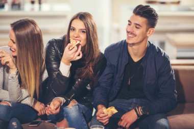Gençler pizza yemek, konuşuyor, gülüyor rahat kıyafetler içinde bir