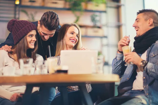 Grupo de jóvenes sentados en una cafetería divirtiéndose — Foto de Stock