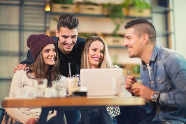 Grupo de jóvenes sentados en una cafetería divirtiéndose — Foto de Stock