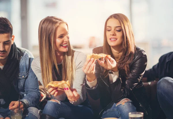 Молодые люди в повседневной одежде едят пиццу, разговаривают, смеются — стоковое фото