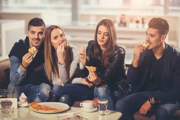 Молодые люди в повседневной одежде едят пиццу, разговаривают, смеются — стоковое фото