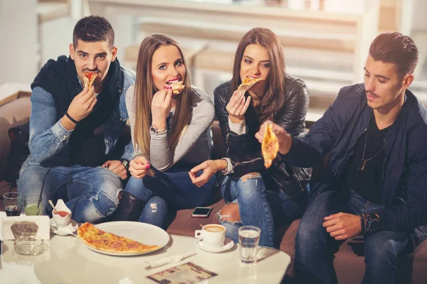 Young people in casual clothes eating pizza, talking, laughing a