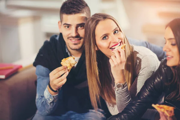 Jovens com roupas casuais comendo pizza, conversando, rindo um — Fotografia de Stock