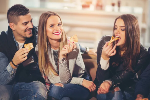 Jovens com roupas casuais comendo pizza, conversando, rindo um — Fotografia de Stock