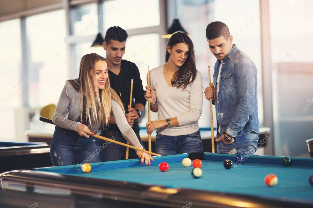 Group of young friends playing billiard