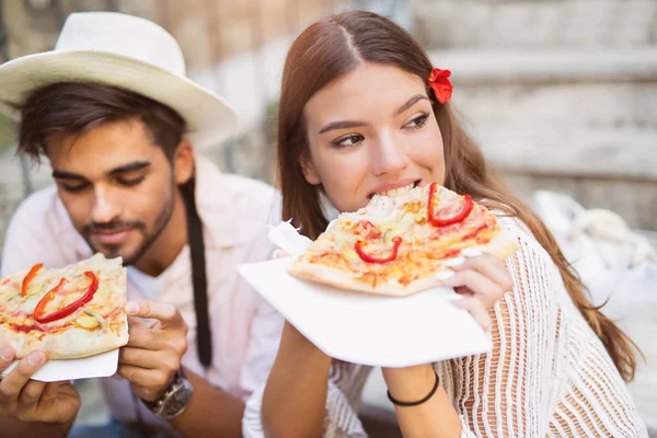 Счастливая пара туристов, поедающих пиццу на улице — стоковое фото