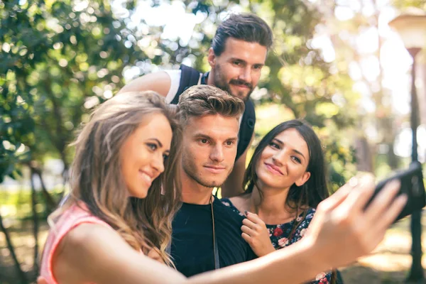 Grupp av fyra roliga vänner tar selfie med en smart telefon i — Stockfoto