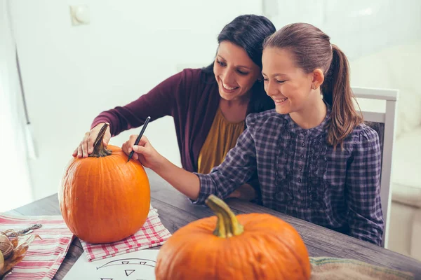 Matka s dcerou vytváření velké oranžové dýně na Halloween — Stock fotografie