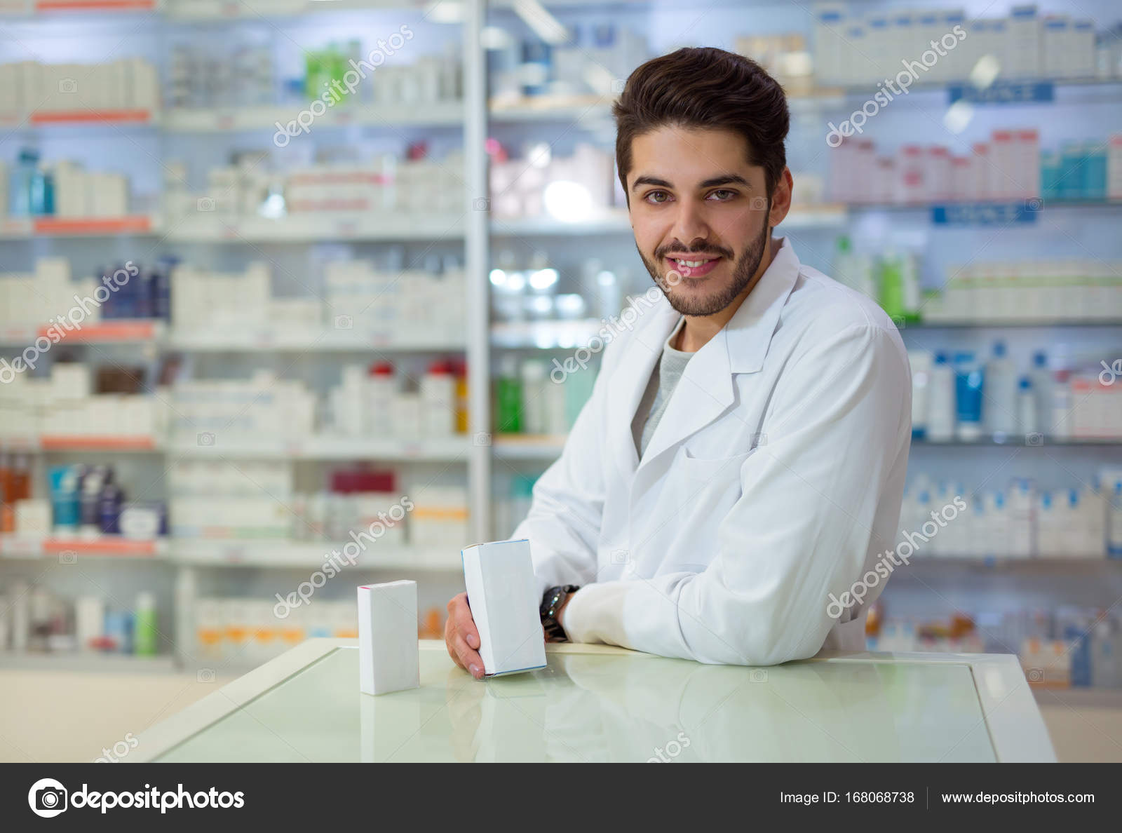 Friendly male pharmacist dispensing medicine holding a box of ta Stock