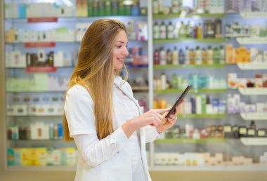 Mutlu genç kadın eczacı eczane arka plan üzerinde tutan 