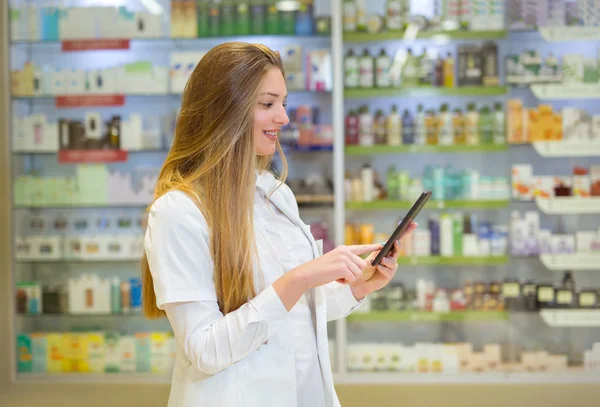 Glücklich junge Apothekerin über Drogerie Hintergrund, hält — Stockfoto
