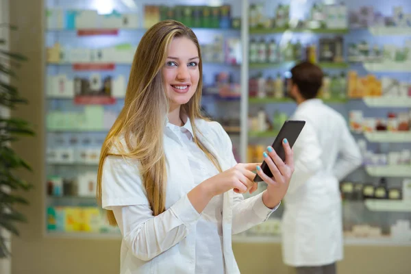 Jovem farmacêutico feliz sobre o fundo farmácia, segurando — Fotografia de Stock