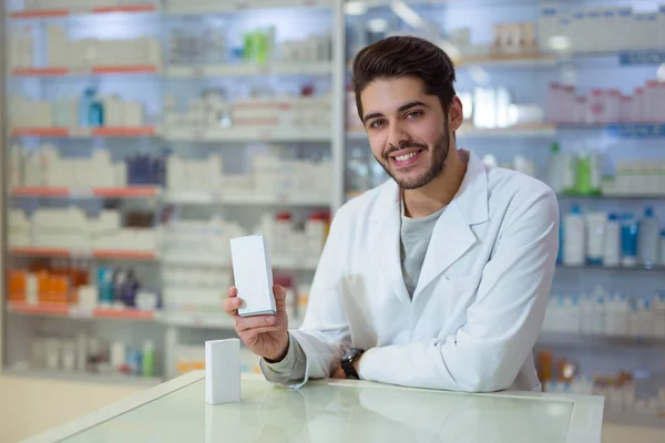 Farmacêutico masculino amigável dispensando medicina segurando uma caixa de ta — Fotografia de Stock