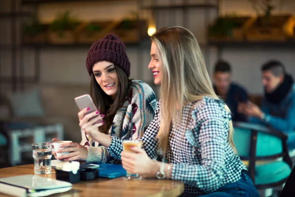 Stock image Two friends enjoying coffee together in a coffee shop and using 