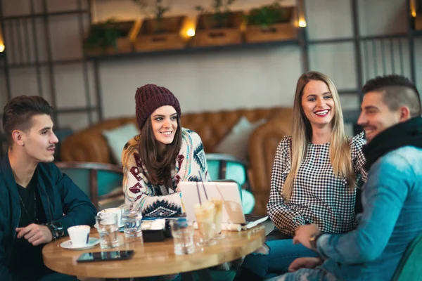 Grupo de jóvenes sentados en una cafetería divirtiéndose — Foto de Stock