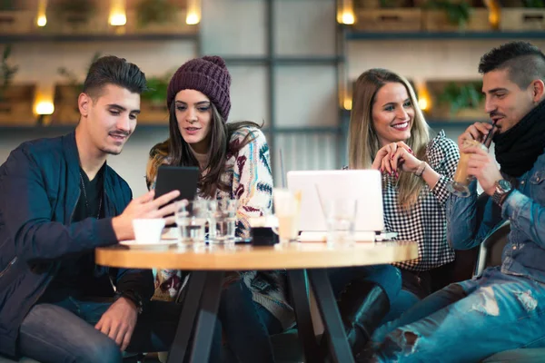 Grupo de jóvenes sentados en una cafetería divirtiéndose — Foto de Stock