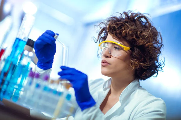 Young female scientist in protective glasses and gloves dropping — Stock Photo, Image