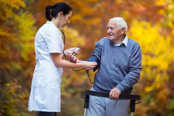 Bloeddruk meten oude patiënt buiten verpleegkundige — Stockfoto