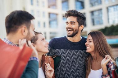 Bir grup arkadaş ellerinde alışveriş çantalarıyla sokakta yürüyorlar.