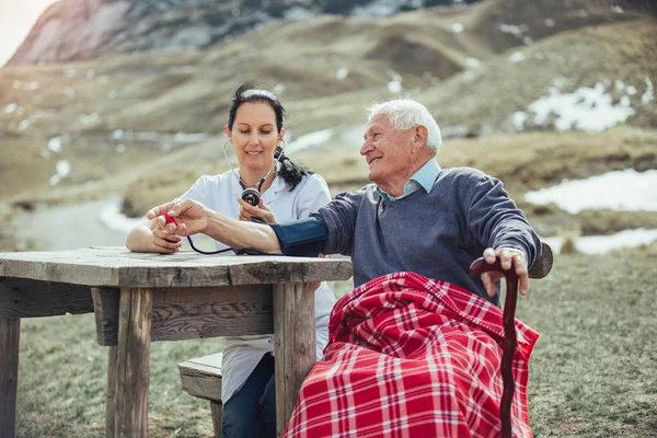 Sjuksköterska med gammal patient utomhus — Stockfoto