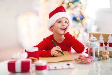 kırmızı şapka Noel Baba'ya mektup yazma küçük mutlu çocuk 