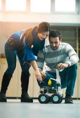 Robotları atölyede test etmek için hazırlayan genç robotik öğrencileri