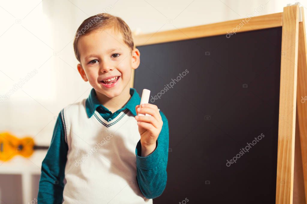 little boy holding with chalk for blackboard, early education concept