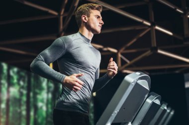 spor salonunda koşu bandı üzerinde çalışan adam. Egzersiz, fitness ve sağlıklı yaşam konsepti