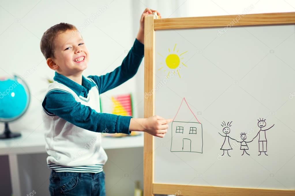 smiling cute little boy drawing on white board. Early education concept