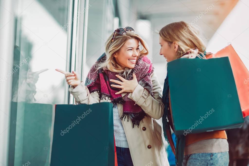Happy female friends shopping. Two beautiful young women enjoying shopping in city
