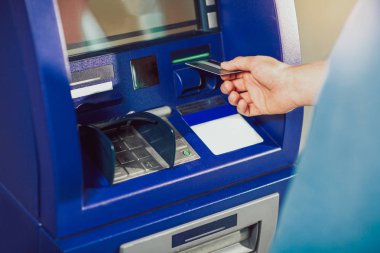 Atm makine para için eklenen bir kredi kartı kullanan adam