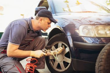 mechanic repairman at car tyre, fitting and balancing adjustment