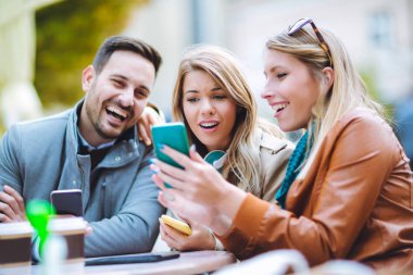 Grup üç mutlu arkadaşıyla kafede smartphone kullanarak