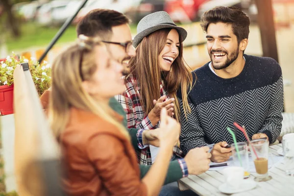 group of happy young people at cafe talking and laughing together