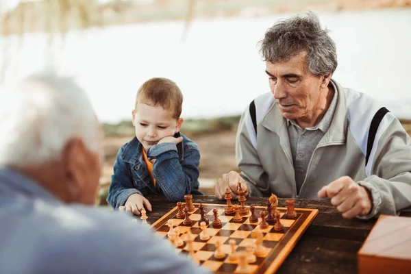Активные Пенсионеры Веселятся Играют Шахматы Парке Проводят Время Маленьким Внуком — стоковое фото