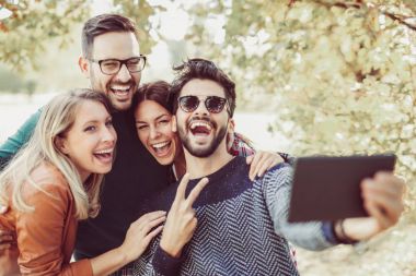 Grup genç mutlu arkadaşlar Bahar park dijital tablet ve alma selfie ile eğleniyor 
