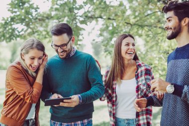 Grup genç mutlu arkadaşlar Bahar park dijital tablet ile eğleniyor 