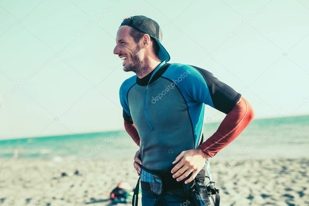 portrait of smiling active male kitesurfer on sandy beach