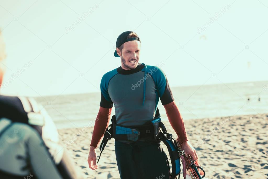 portrait of smiling active male kitesurfer on sandy beach