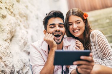 Merdivenlerde oturan ve tablet bilgisayar başında arıyor Romantik Çift