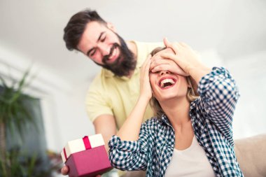 gülümseyen genç adam şaşırtıcı neşeli kadın evde hediye kutusu